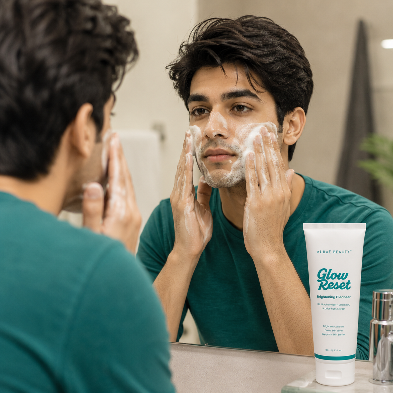 A man applying Glow Reset Brightening Cleanser by Auraé Beauty to his face while looking into a bathroom mirror. 