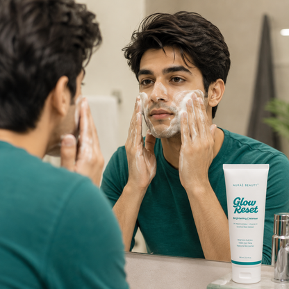 A man applying Glow Reset Brightening Cleanser by Auraé Beauty to his face while looking into a bathroom mirror. 